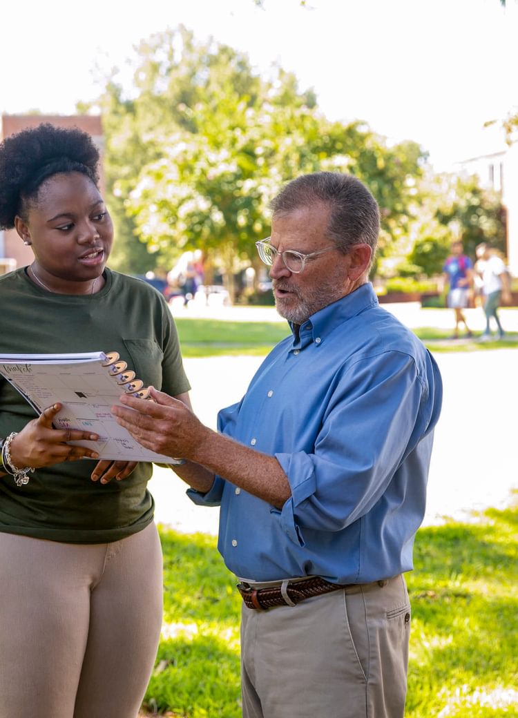 a female student speaks with her professor outside