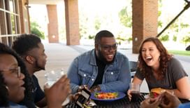 a group of students eat lunch on the patio