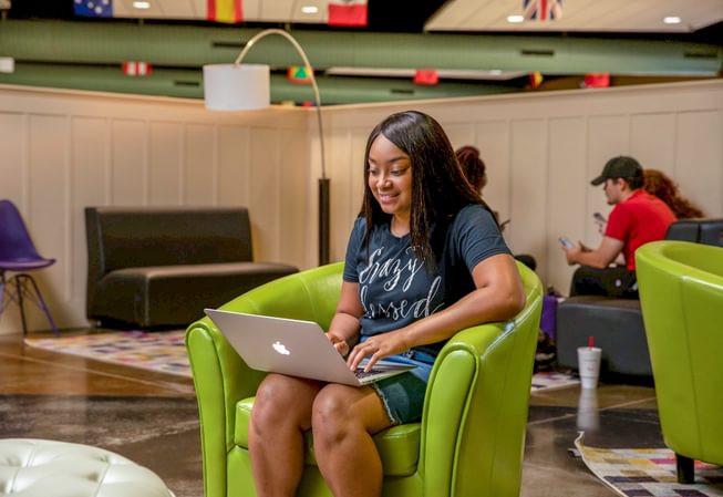 a student uses her computer in a common area on campus