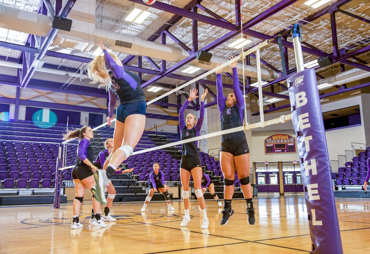 a volleyball player jumps in the air to spike the ball