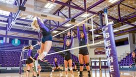a volleyball player jumps in the air to spike the ball