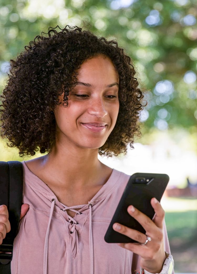 a female student looks at her phone outdoors
