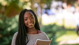 an outdoor portrait of a female student holding a notebook