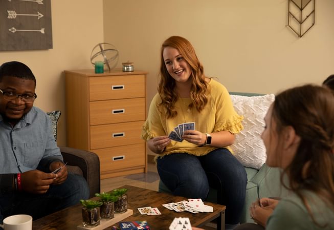 several students playing cards in a dorm room