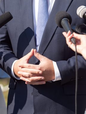an emergency management professional gathers in front of microphones