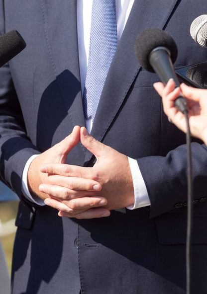 an emergency management professional gathers in front of microphones