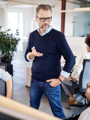 a business admin talks to several employees in an office situation