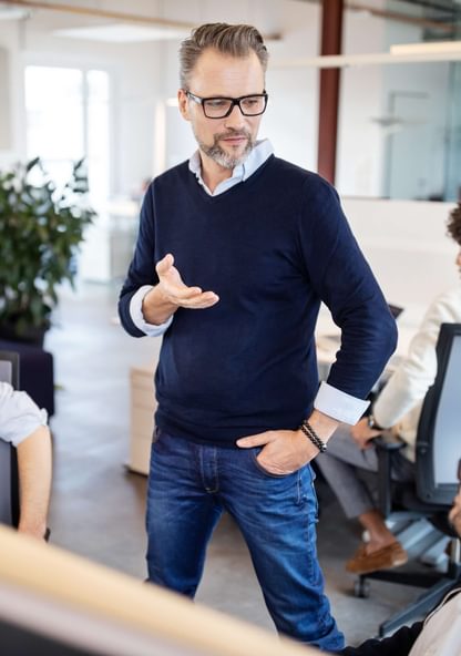 a business admin talks to several employees in an office situation