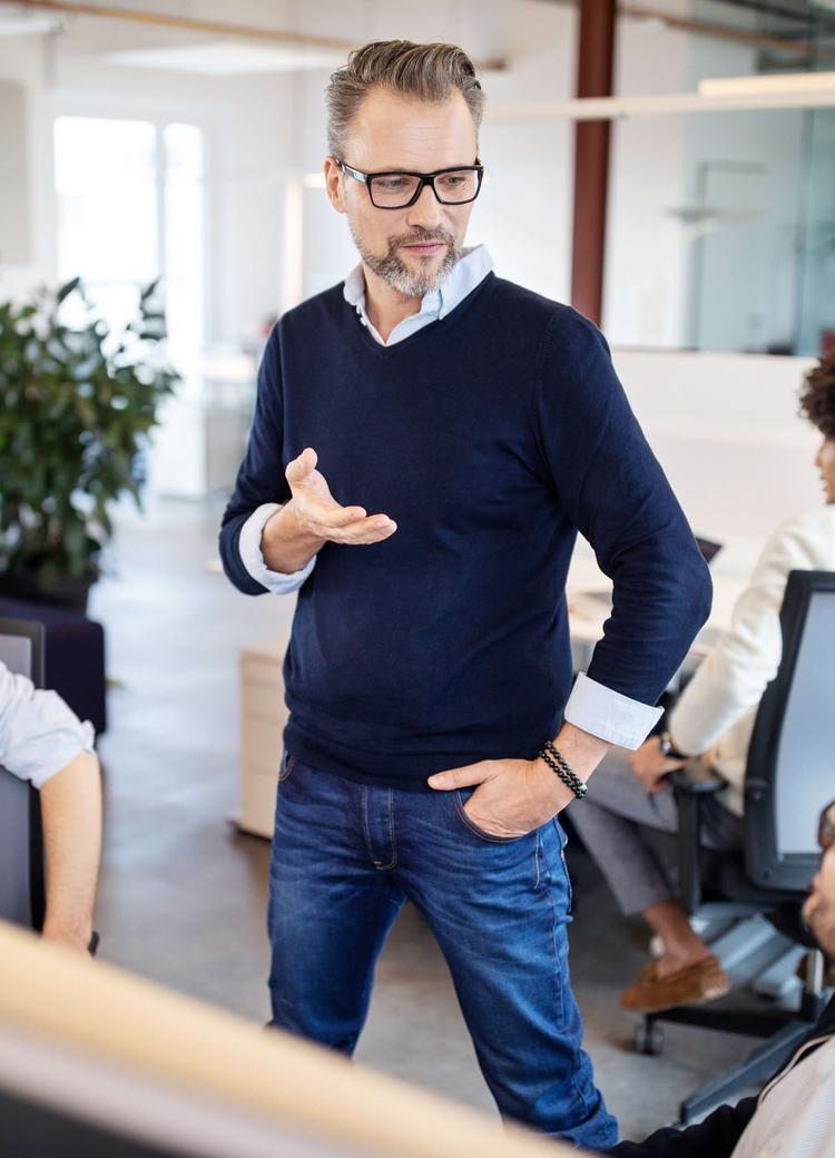 a business admin talks to several employees in an office situation