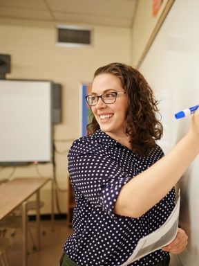 a teacher leads class while working on the whiteboard