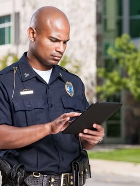 an officer uses a tablet in a parking lot