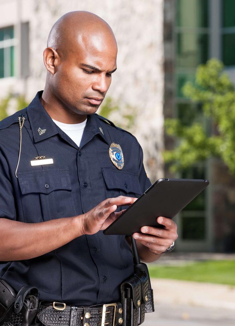 an officer uses a tablet in a parking lot