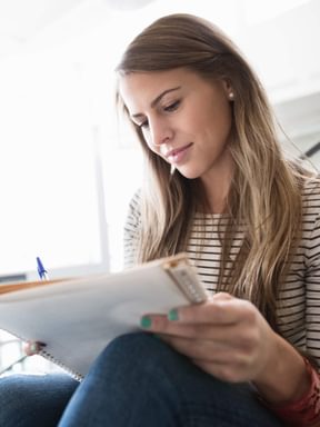 an English student makes some notes in a notebook