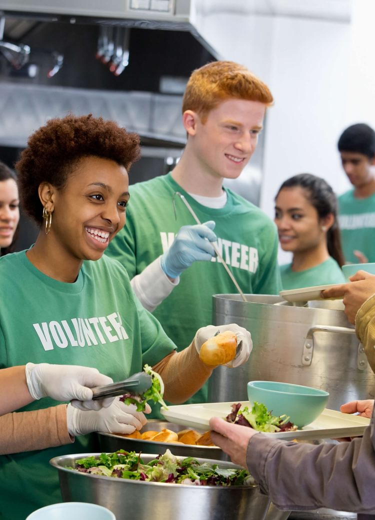 several individuals work at a soup kitchen for the homeless