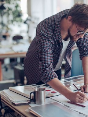 a student takes notes on some work at his desk