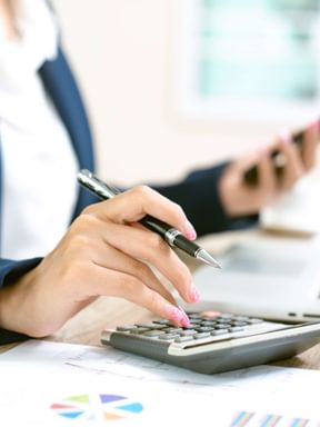 a female business admin enters some accounting figures into her calculator