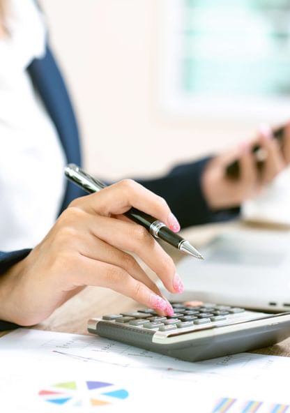 a female business admin enters some accounting figures into her calculator