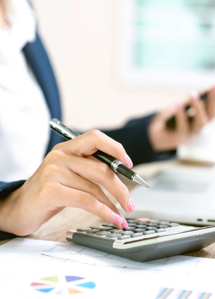 a female business admin enters some accounting figures into her calculator