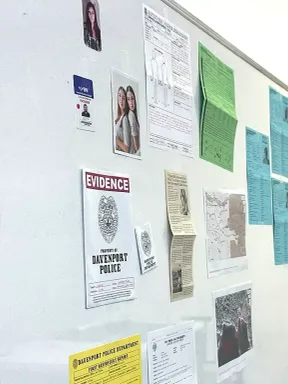 A crime scene board with evidence photos, police reports, and case documents used in a criminal justice class.