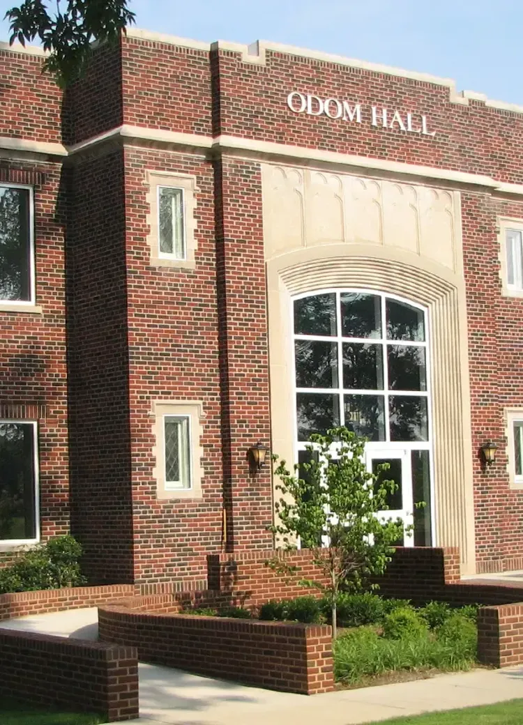 Exterior of Odom Hall with a grand glass entryway and manicured landscaping.