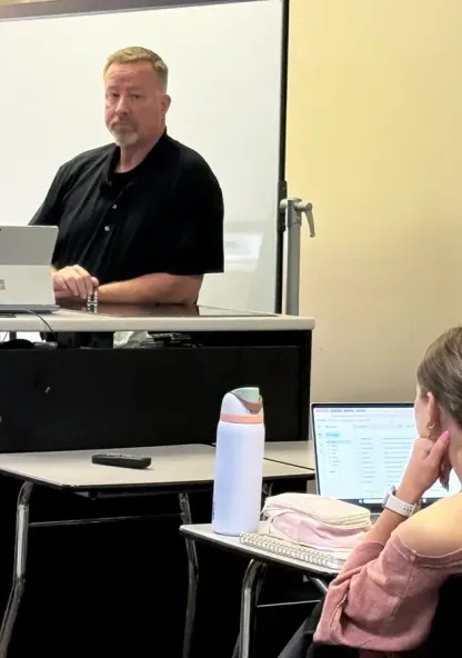 Two law enforcement professionals presenting to a student in a college classroom.