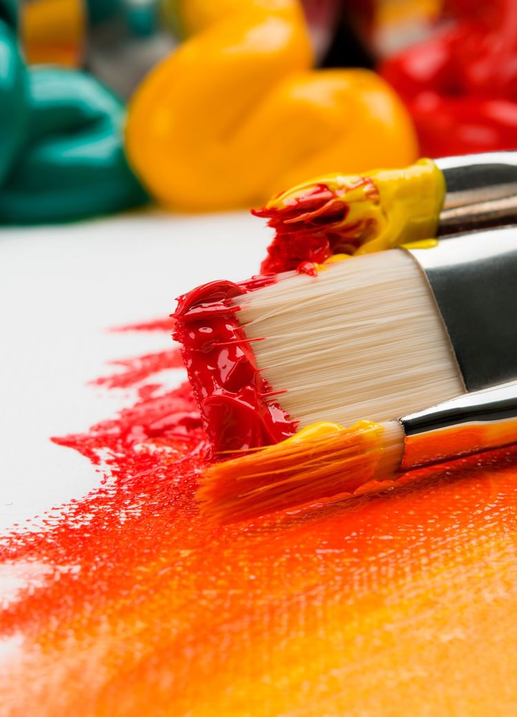 paint brushes on a vibrantly painted canvas