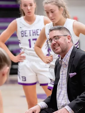 Bethel women’s basketball coach talks with players during a timeout.