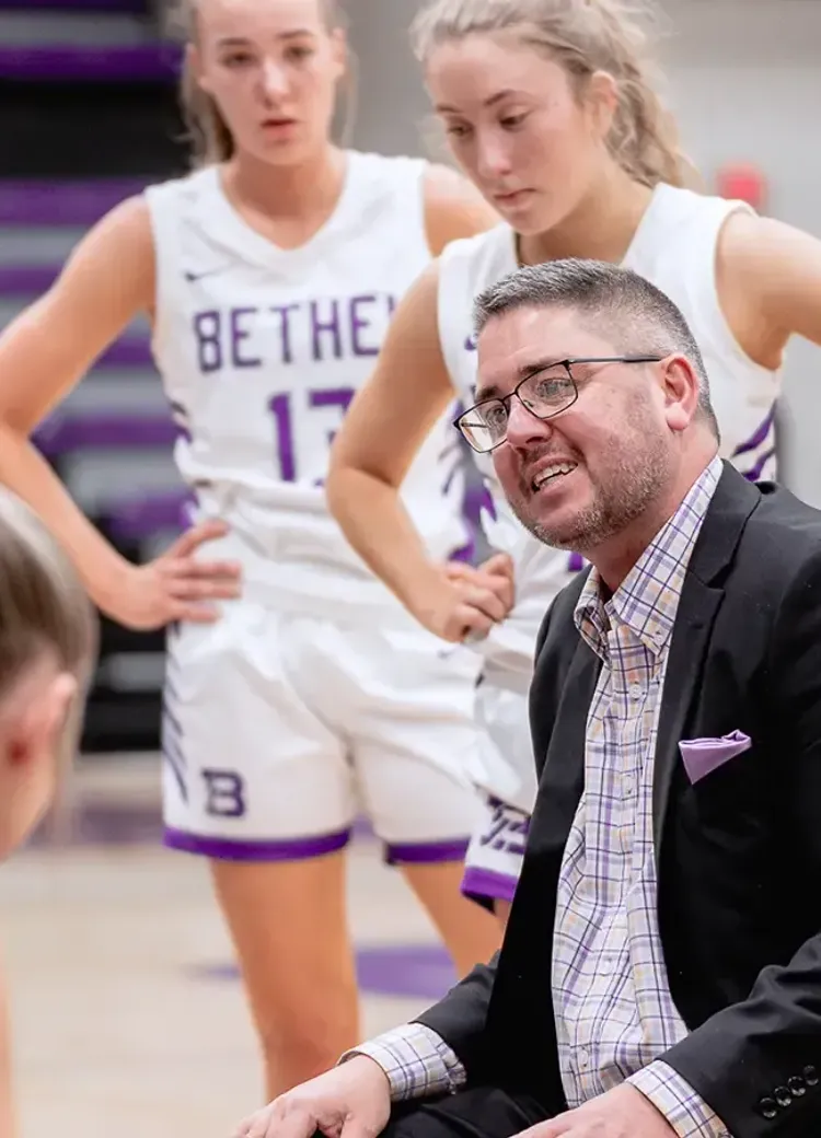 Bethel women’s basketball coach talks with players during a timeout.