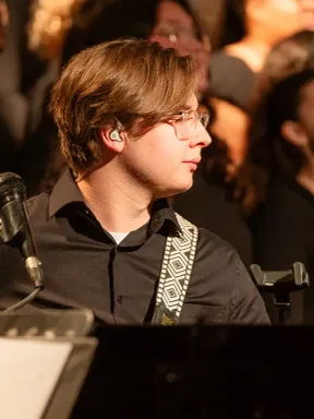 Student playing bass guitar during a musical performance