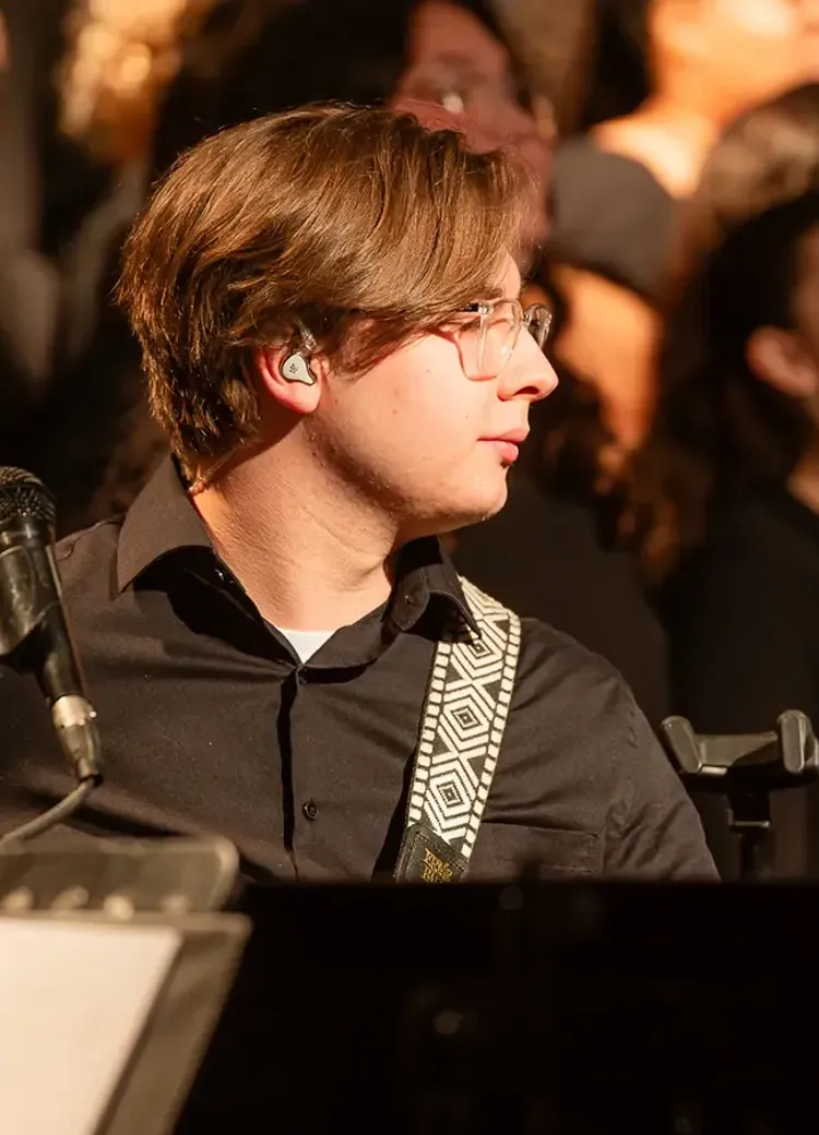 Student playing bass guitar during a musical performance