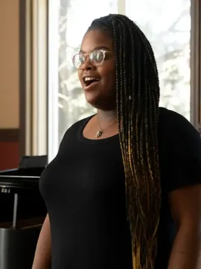 A music student sings while a pianist accompanies her during a performance.