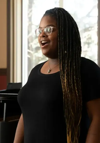 A music student sings while a pianist accompanies her during a performance.