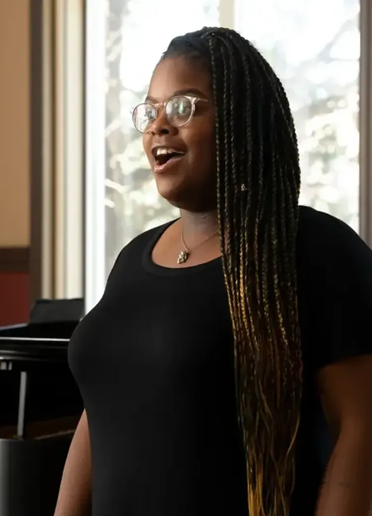 A music student sings while a pianist accompanies her during a performance.
