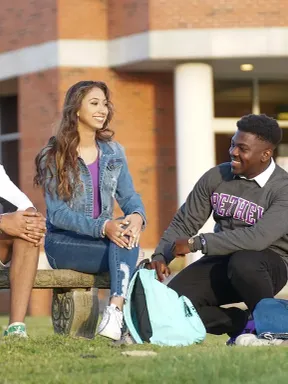Four Bethel students sit and talk together outside the library.