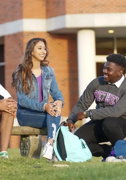 Four Bethel students sit and talk together outside the library.