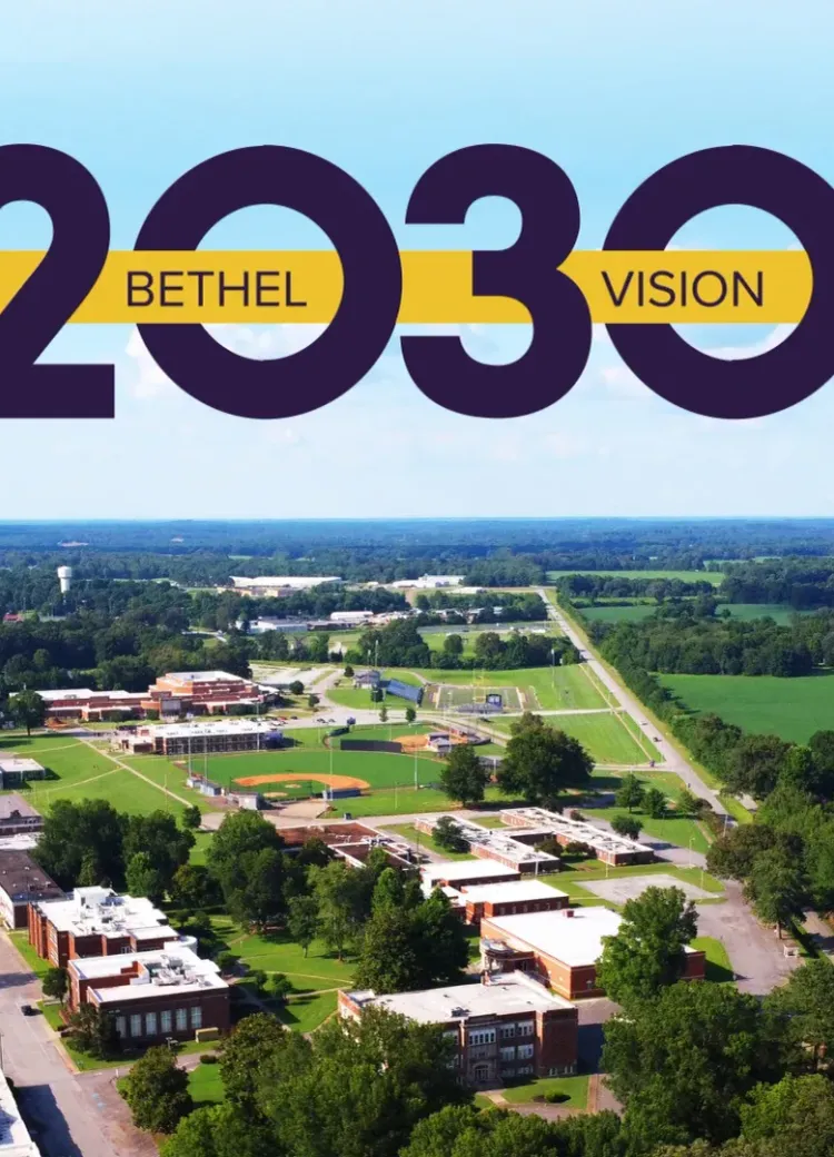 Aerial shot of Bethel University's campus beneath the gold-and-purple Bethel Vision 2030 logo.